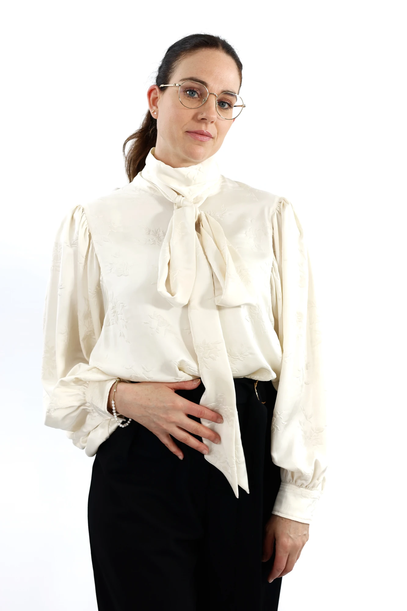 Halbkörper-Portrait einer Frau mit Brile im kremigen Hemd